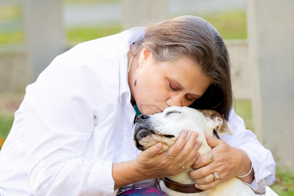 Human hugging a white dog as therapy dog from The Right Paw