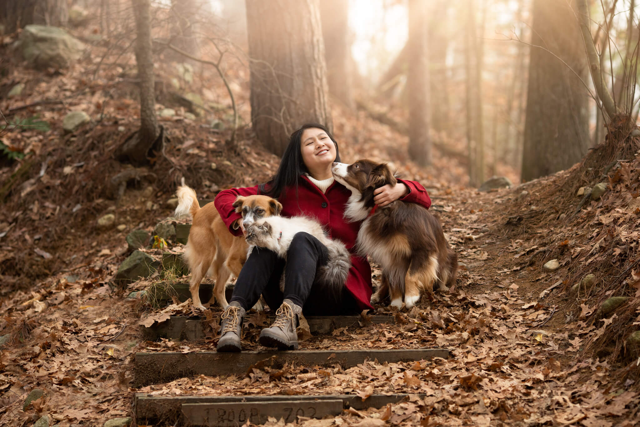 woman in red jacket with 2 dogs and a cat laughing in the woods Bark N Roll Reading MA